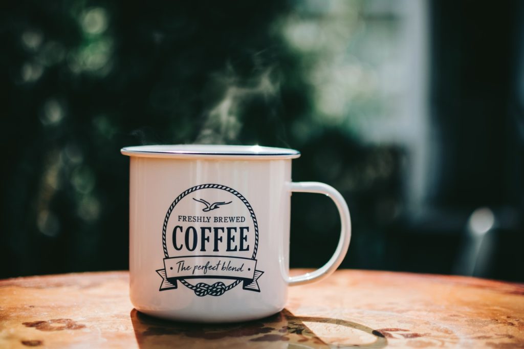 Steaming Hot, Logoed Cup of Coffee Sitting On a Table